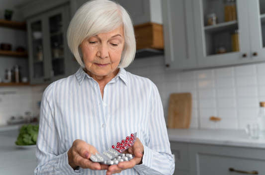 Older adult examining multiple blister packs of pills in a modern kitchen — lifestyle image for senior wellness, medication management, or pharmacy product.