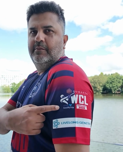 Man wearing a sports jersey with branding, pointing towards the camera with a scenic background.